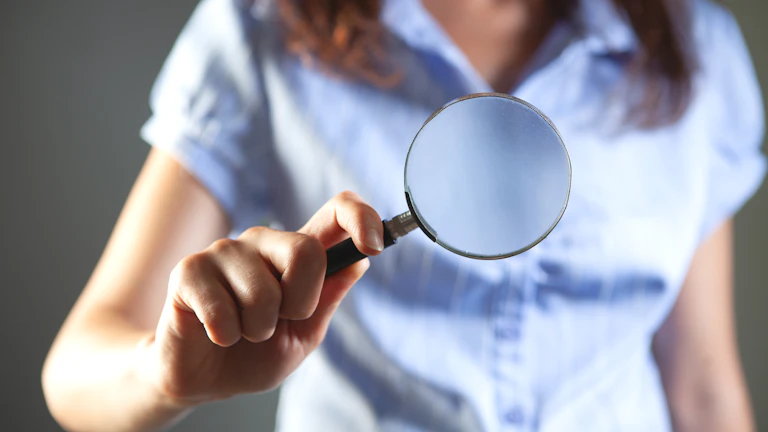 보험 서류를 돋보기로 자세히 살펴보는 모습